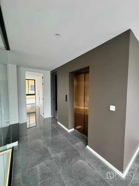 Home Office for rent or sale in Lat Phrao, Bangkok - Bright corridor featuring a bronze private lift and polished gray marble floors.