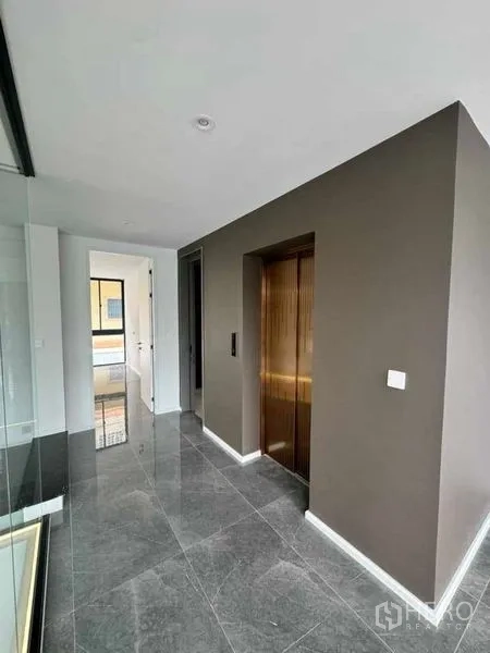 Home Office for rent or sale in Lat Phrao, Bangkok - Bright corridor featuring a bronze private lift and polished gray marble floors.