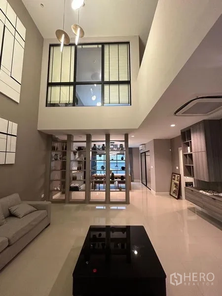 Townhouse for sale in Saphan Sung, Bangkok - Open‑plan living zone with display cabinetry, TV wall and stairs to upper floor.