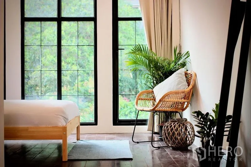 Townhouse for rent in Sathon, Bangkok - Cozy reading nook by floor-to-ceiling windows with rattan chair and indoor plants
