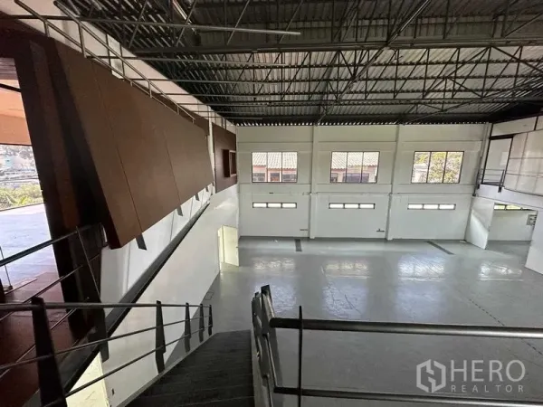 Warehouse for rent in Phra Khanong, Bangkok - Open clear-span warehouse floor viewed from the staircase, featuring tall windows and polished concrete.