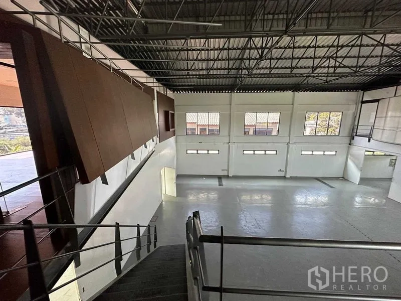 Warehouse for rent in Phra Khanong, Bangkok - Open clear-span warehouse floor viewed from the staircase, featuring tall windows and polished concrete.