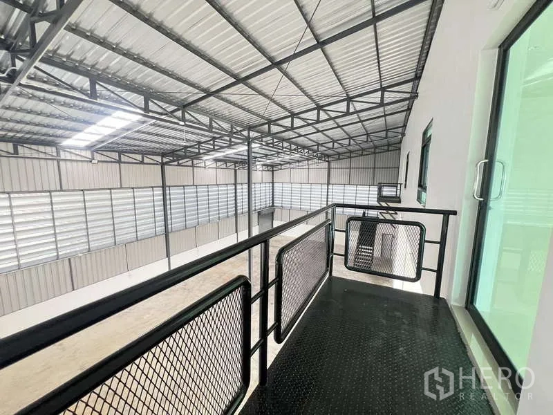 Warehouse for rent or sale - Mezzanine platform overlooking the warehouse floor with metal handrail and roof trusses.