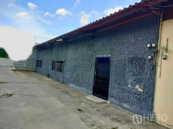 货栈 出租在Suan Luang, Bangkok - 仓库外立面配金属屋顶与粗纹外墙，前方为宽阔装卸车道。