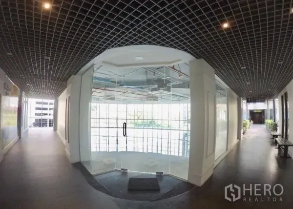 Retail Space for rent in Khlong Toei, Bangkok - Modern corridor with a glass storefront entrance to the retail unit and grid ceiling.