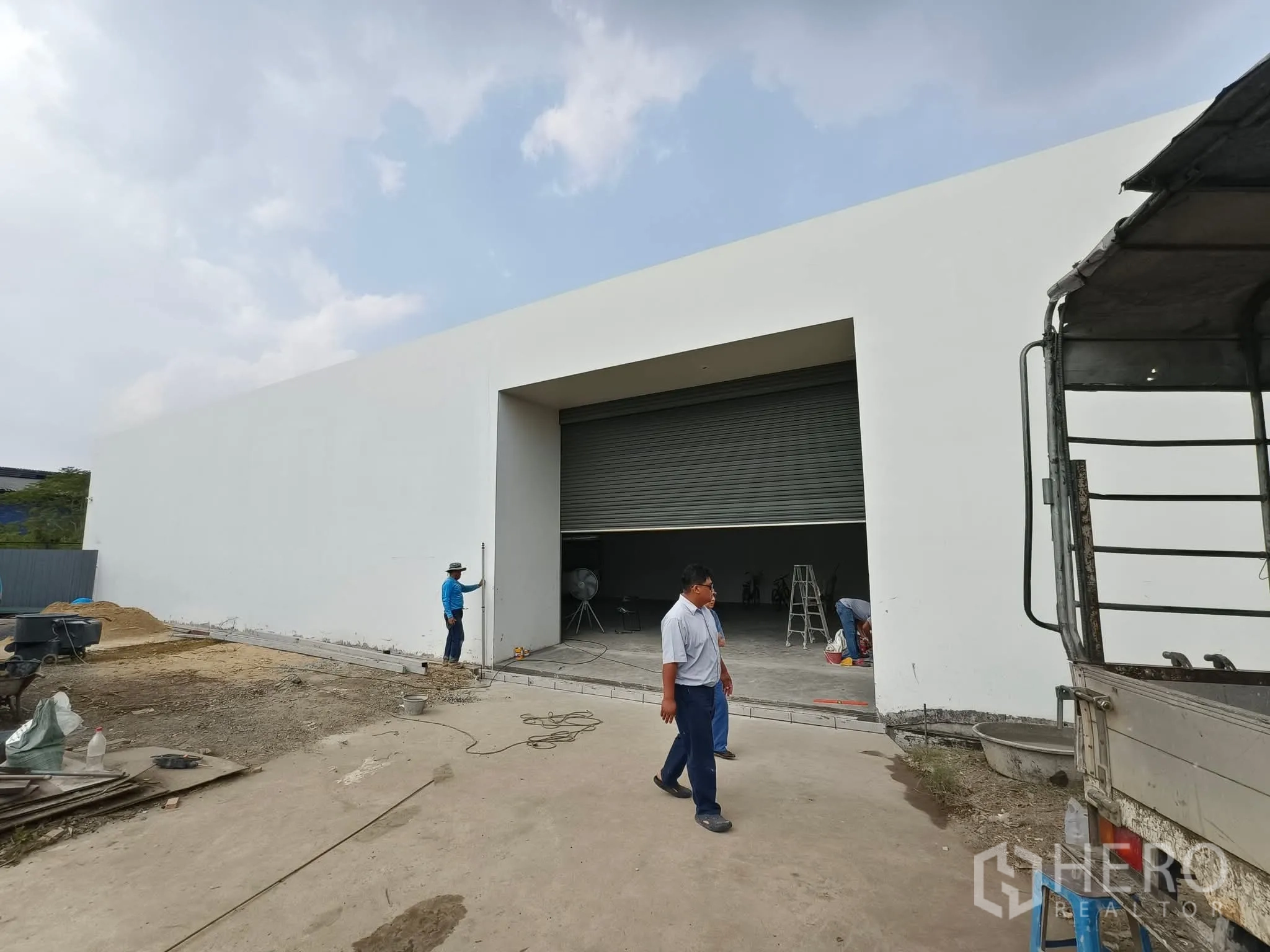 โกดัง for rent in Sai Mai, Bangkok - ภายนอกโกดังสีขาวสมัยใหม่ พร้อมประตูม้วนขนาดใหญ่และลานโหลดสินค้า
