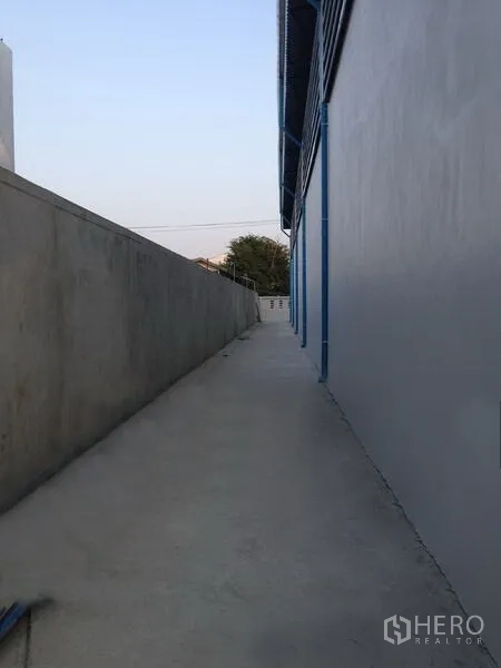 Warehouse for rent in Mueang Samut Prakan, Samut Prakan - Concrete service walkway running along the exterior wall of the warehouse compound.