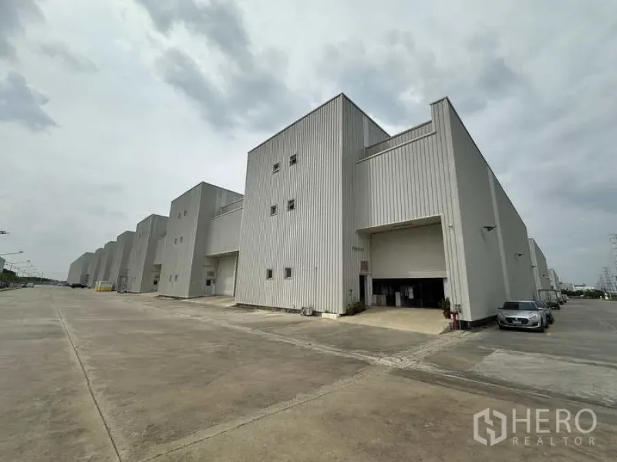 Factory for rent in Khlong Luang, Pathum Thani - Row of modern high-bay factory buildings with wide truck-friendly driveway and loading bays.