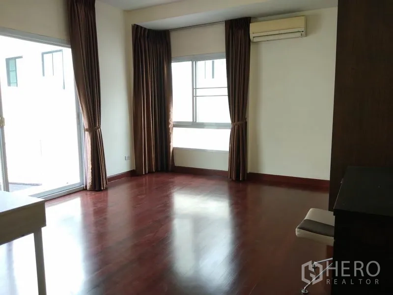 Detached House for rent in Watthana, Bangkok - Large upstairs room with wood floors, air conditioning and sliding door to a balcony.