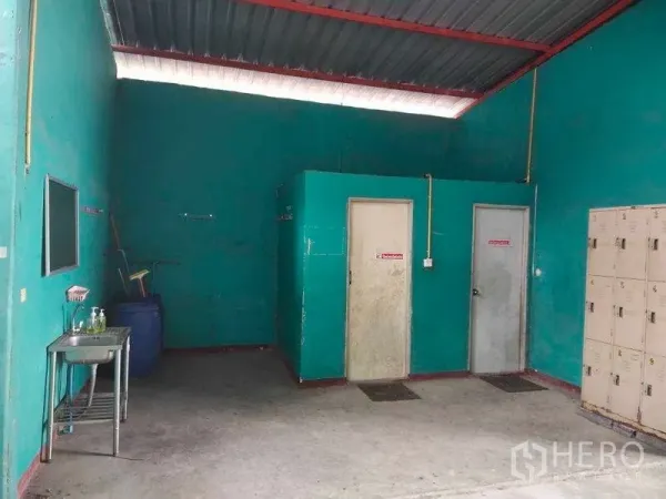 Warehouse for sale in Lam Luk Ka, Pathum Thani - Warehouse staff area featuring lockers, a washbasin, and two restroom doors.