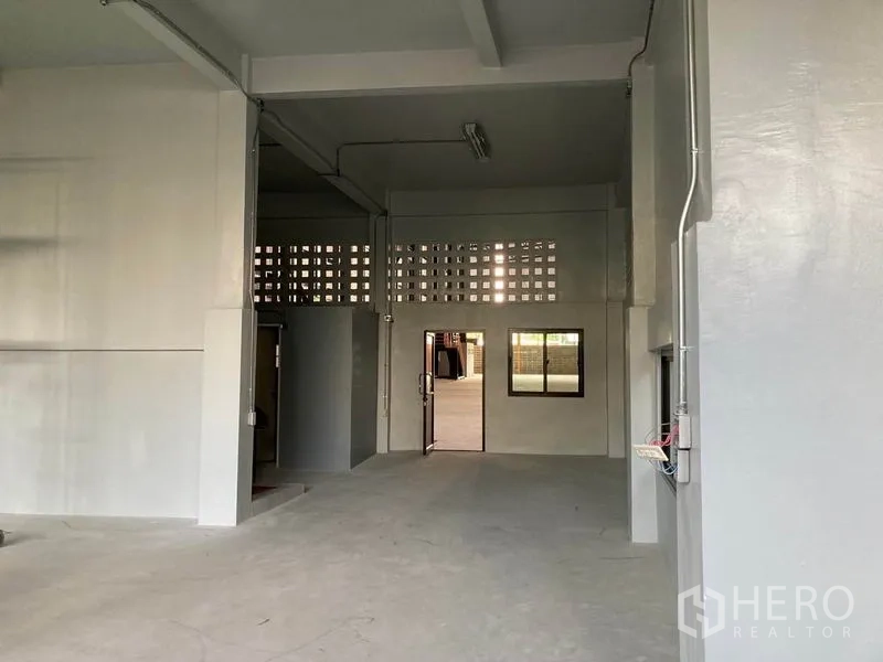 Warehouse for rent in Khlong Toei, Bangkok - Ground-floor office or shop-house entry inside the warehouse with door, interior windows and exposed service conduits.