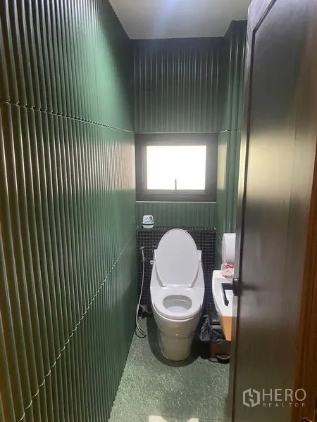 店屋 出租 - 紧凑卫生间，绿色立体墙板、窗户与马桶。