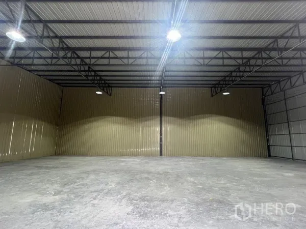 Warehouse for rent in Phra Khanong, Bangkok - Empty warehouse interior featuring a high steel-truss ceiling, LED high-bay lights, and a concrete floor.