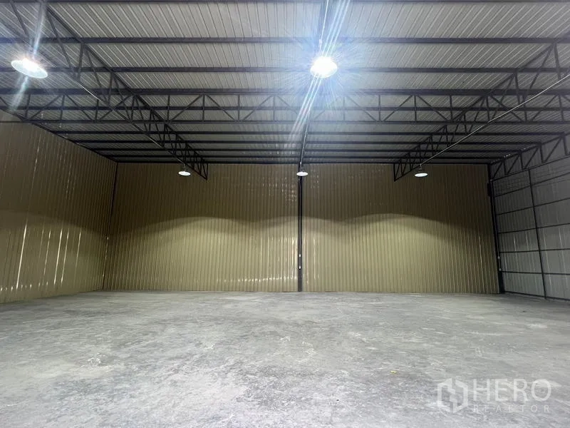 Warehouse for rent in Phra Khanong, Bangkok - Empty warehouse interior featuring a high steel-truss ceiling, LED high-bay lights, and a concrete floor.
