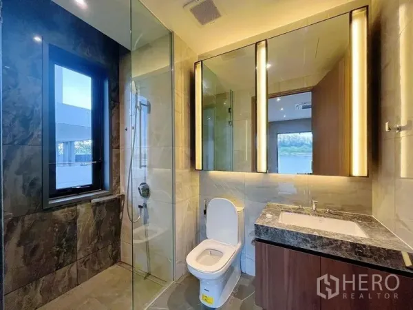 Detached House for sale in Bang Phli, Samut Prakan - Modern bathroom with glass shower, backlit mirror, stone tiles, and a window.
