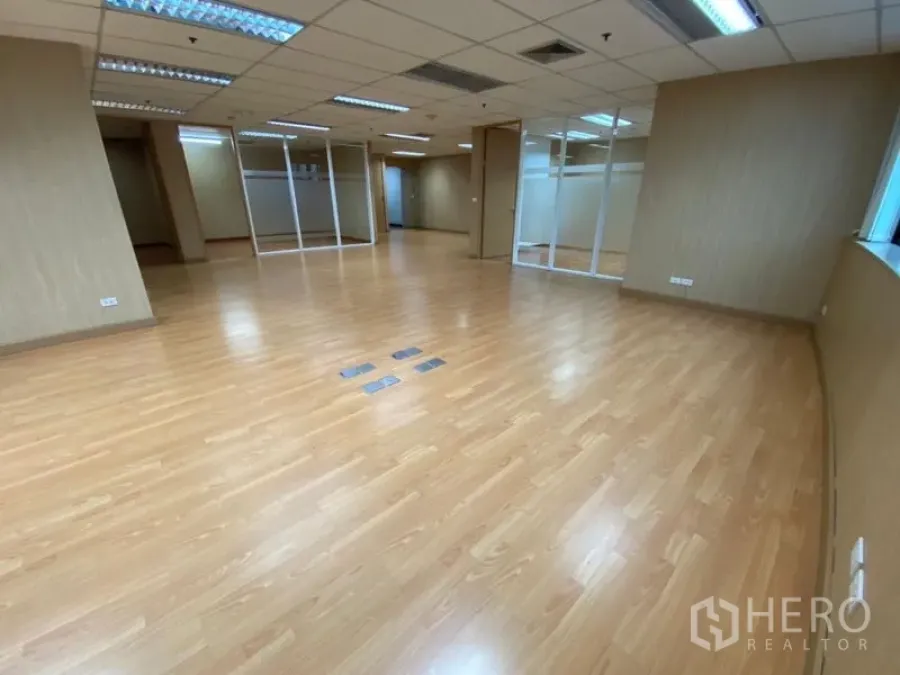 Office Space for rent in Watthana, Bangkok - Open-plan office area with laminate floors, fluorescent lights, and glass-partitioned meeting rooms.
