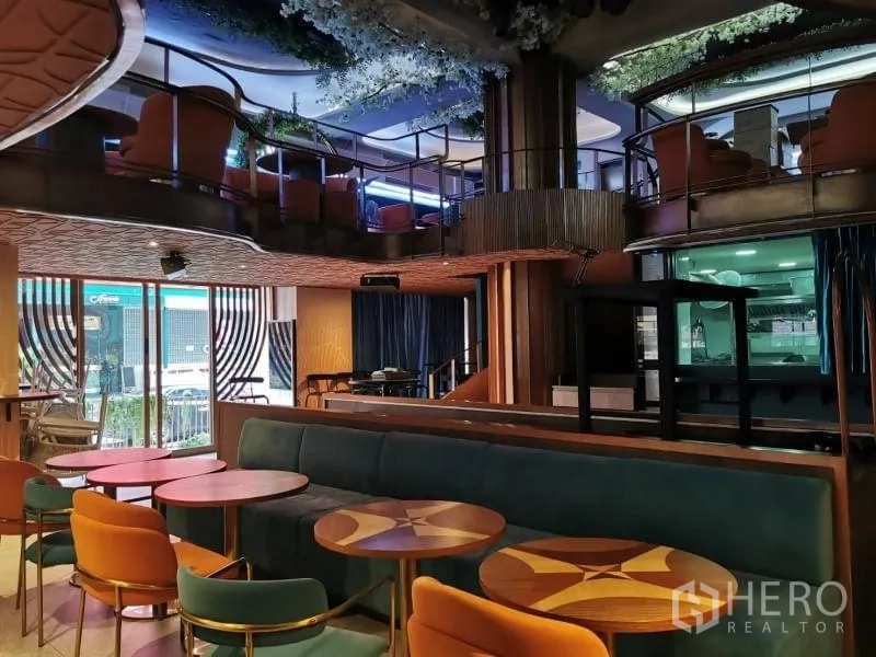 Retail Space for rent - Double-height retail lounge with teal banquette, round wood tables, and mezzanine seating.