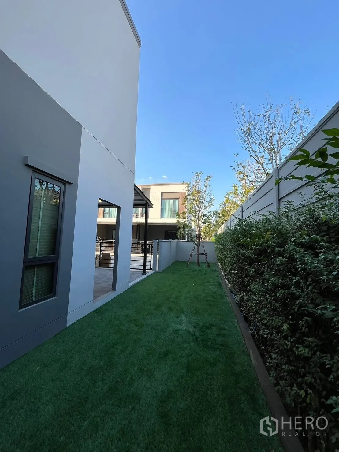 Townhouse for rent in Bang Phli, Samut Prakan - Long side yard with turf lawn, privacy fence, and neighboring modern townhomes.