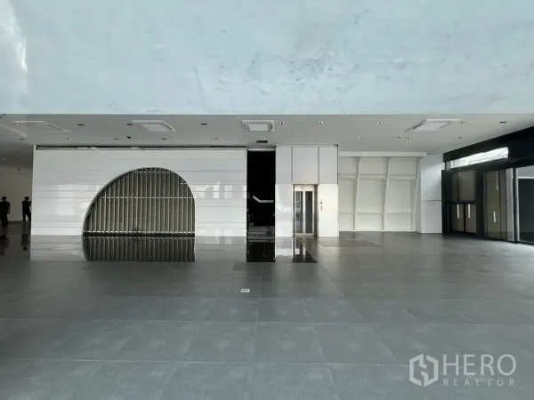 Retail Space for rent in Watthana, Bangkok - Wide showroom area featuring a passenger lift, curved feature wall, spot lighting, and polished flooring.