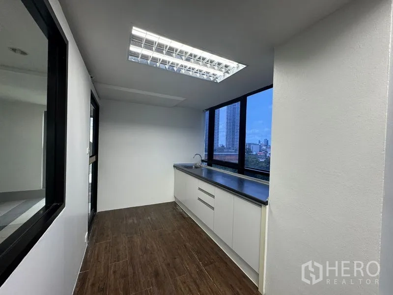Office Space for rent in Sathon, Bangkok - Compact pantry with long countertop, sink, and windows facing the city.