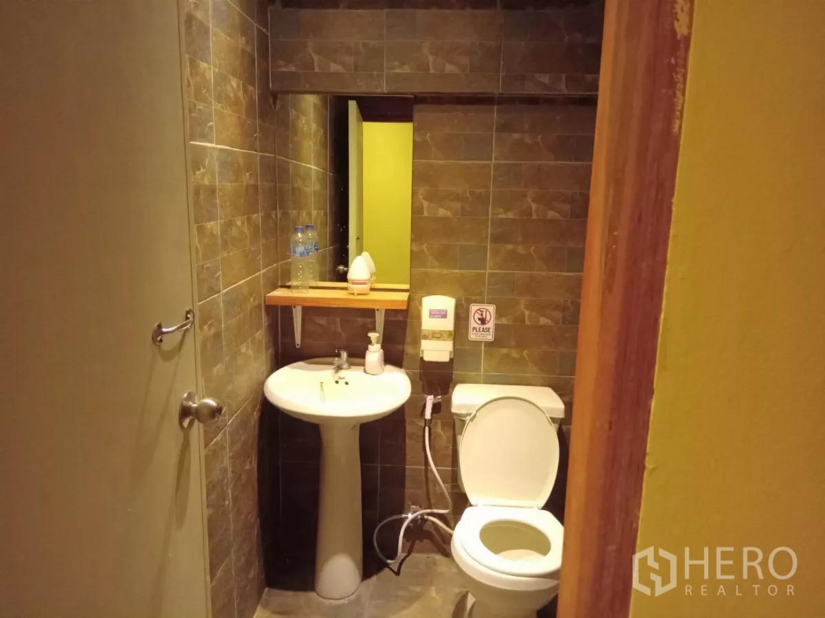 Detached House for rent in Phaya Thai, Bangkok - Compact restroom with pedestal sink and brown wall tiles.