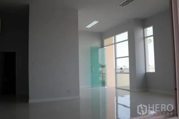 Factory for rent or sale in Lam Luk Ka, Pathum Thani - Corner office with floor-to-ceiling windows and a glass door bringing natural light.