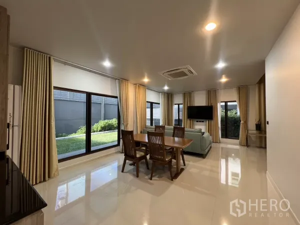 Detached House for rent or sale in Bang Kapi, Bangkok - Bright lounge and dining space with full-height windows overlooking the lawn