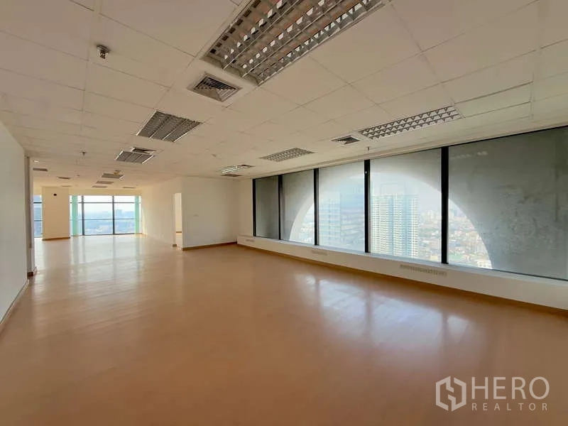 Office Space for rent in Chatuchak, Bangkok - Long open office area with full-height windows and ceiling fluorescent lights.