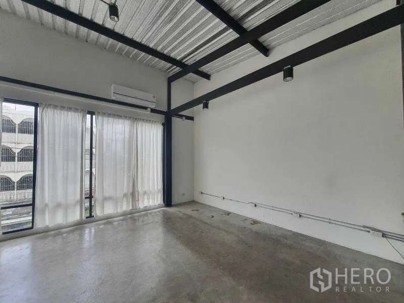 Retail Space for rent in Sathon, Bangkok - Minimalist retail room with track lighting, black steel beams, polished concrete floor, and sheer floor-to-ceiling curtains.