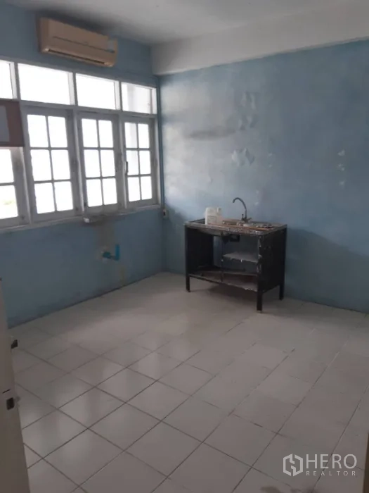 Townhouse for rent in Khlong Toei, Bangkok - Basic kitchen with tiled floor, blue walls, windows and a single sink unit.