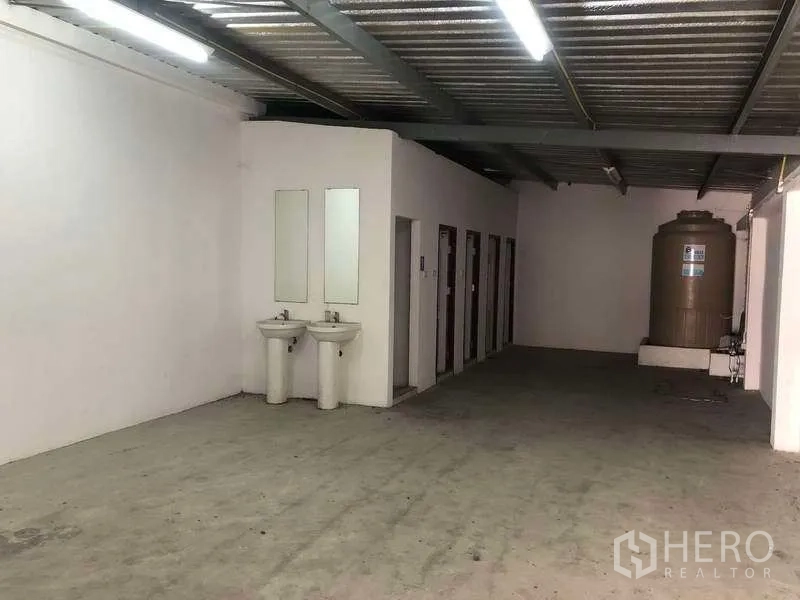 Factory for rent or sale in Samut Prakan - Utility area with multiple restroom stalls, twin sinks and a water storage tank.
