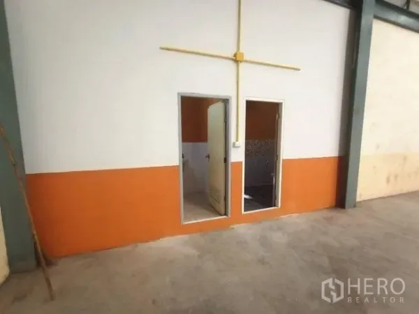 Factory for rent in Mueang Samut Sakhon, Samut Sakhon - Factory utility block with doors to a restroom and storage, finished in orange and white.