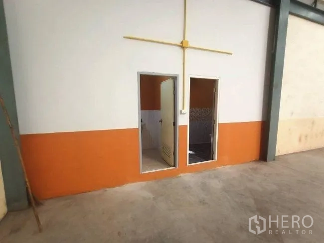 Factory for rent in Mueang Samut Sakhon, Samut Sakhon - Factory utility block with doors to a restroom and storage, finished in orange and white.