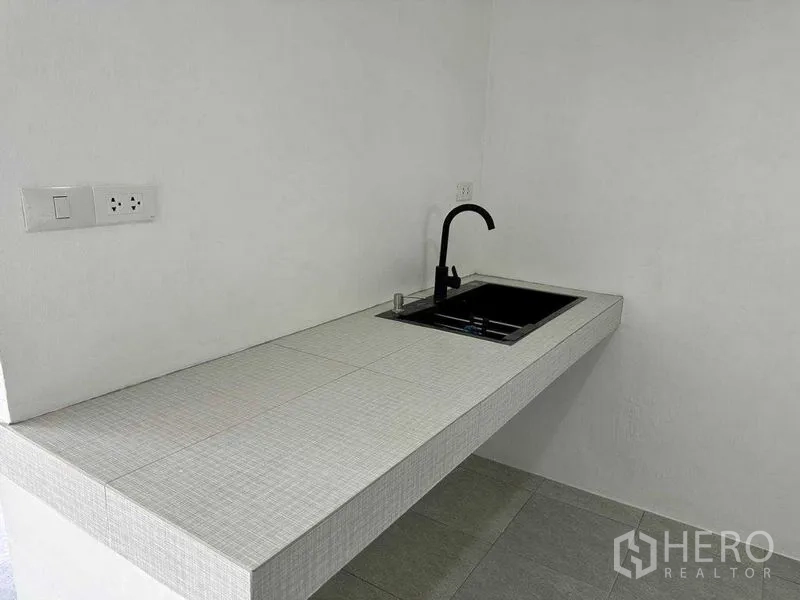 办公空间 出租或出售在Khlong Toei, Bangkok - 紧凑茶水间，瓷砖台面、黑色龙头与电源插座。