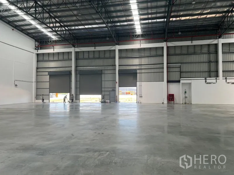 Factory for rent in Bang Pakong, Chachoengsao - Warehouse interior with multiple roller doors to the yard, smooth floor and high roof trusses.