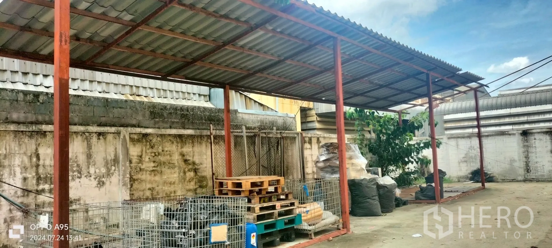 Factory for rent in Khlong Luang, Pathum Thani - Covered loading and storage zone with steel roof and pallets.