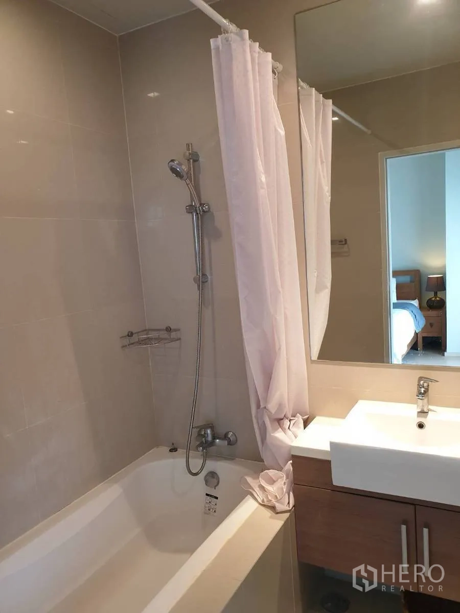 Condominium for rent or sale in Bangkok - Bathroom with bathtub, shower over tub, large mirror and vanity.