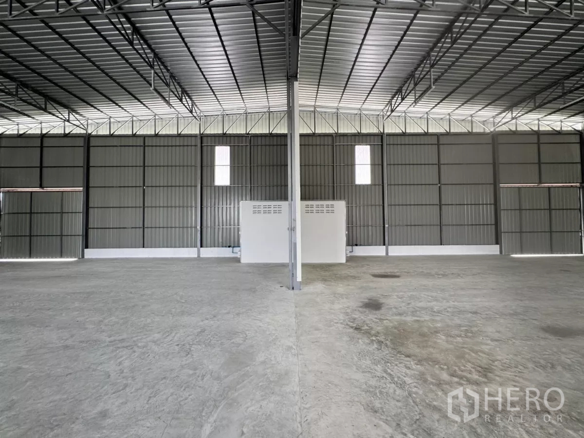 货栈 出租在Lam Luk Ka, Pathum Thani - 对称视角的内部空间，中央立柱、小型服务间与大面积地坪。