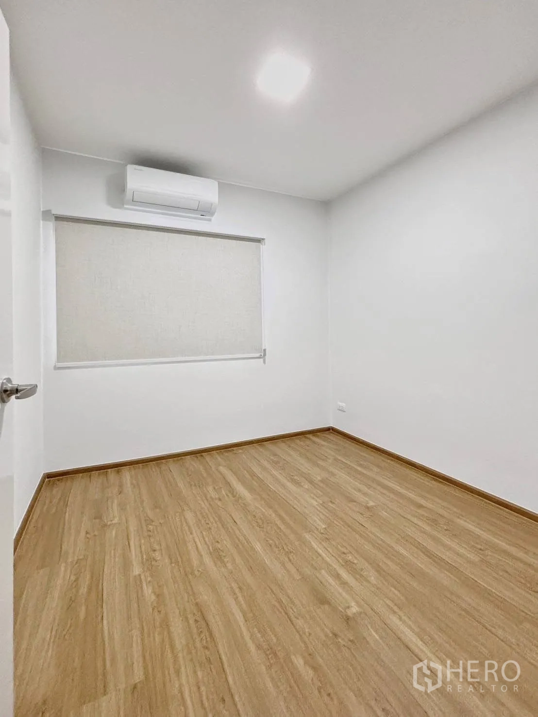 Townhouse for rent in Bang Phli, Samut Prakan - Empty bedroom with wood-look flooring, window blind, and air conditioner.