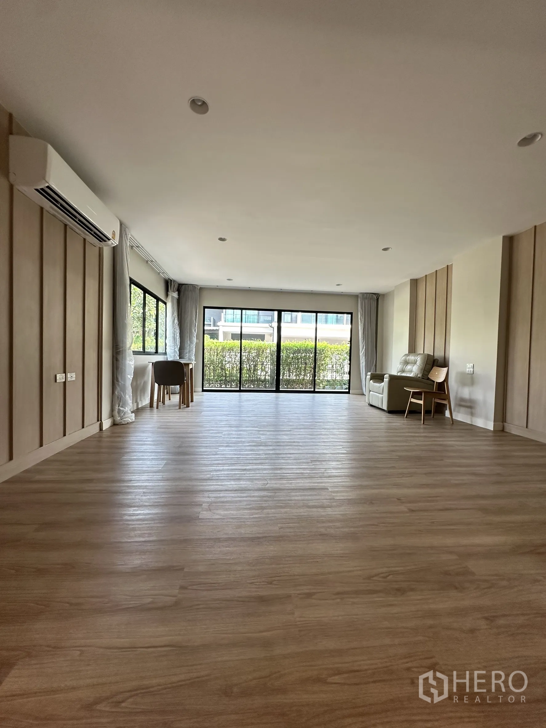 Detached House for sale in Lam Luk Ka, Pathum Thani - Wide room facing sliding doors to a hedged garden, equipped with air conditioner.