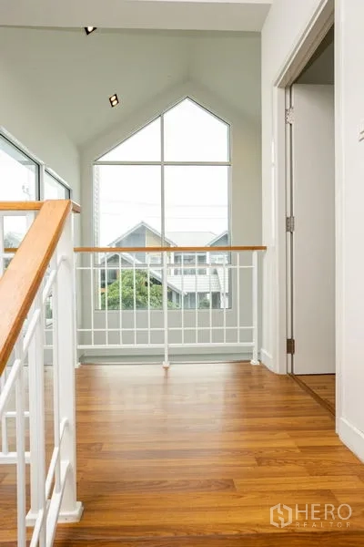Detached House for rent or sale in Lam Luk Ka, Pathum Thani - Landing area facing a gable window and railing, wood flooring throughout.