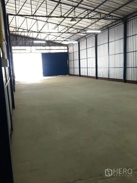 Warehouse for rent in Bang Kapi, Bangkok - Long, column-free warehouse bay with high ceiling, polished concrete floor and a large front door allowing easy loading.