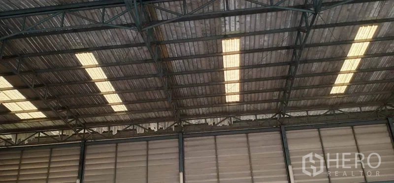 Warehouse for rent in Khlong Luang, Pathum Thani - Interior steel truss roof with translucent skylight panels providing natural light inside the warehouse.