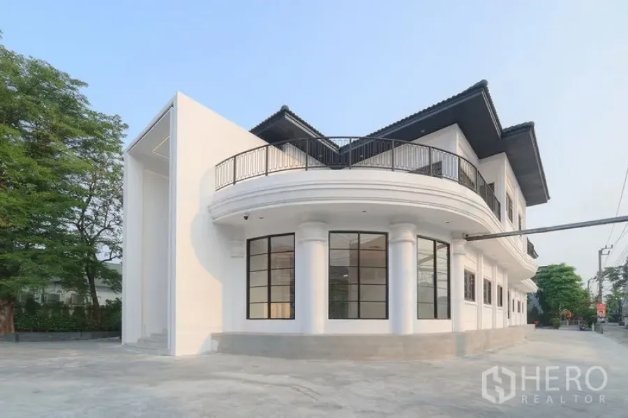 Office Space for rent in Bang Na, Bangkok - Curved corner elevation with columns, floor‑to‑ceiling windows and a wraparound balcony amid greenery.