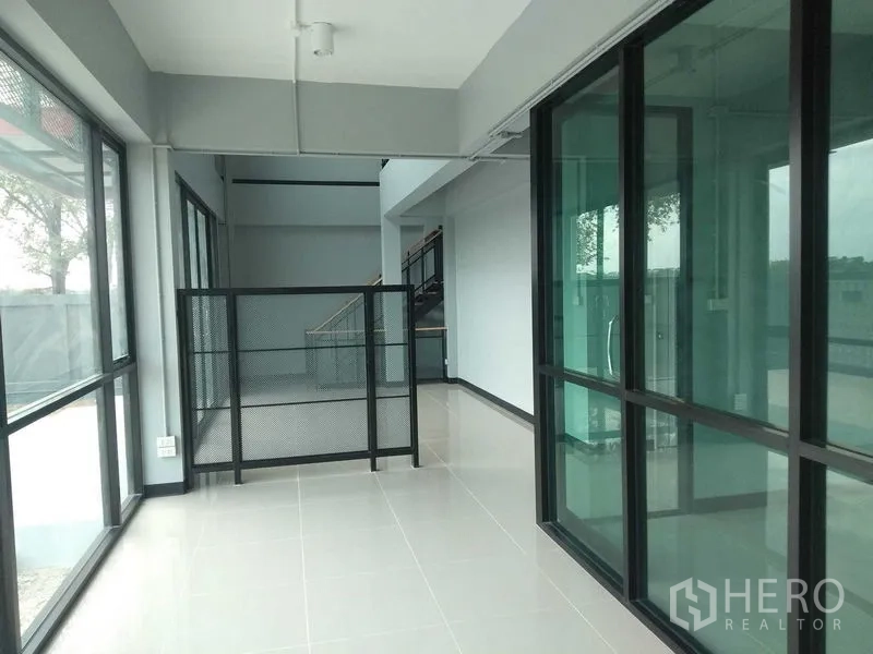 Factory for rent or sale - Bright glass-walled office corridor with sliding doors and safety railing.
