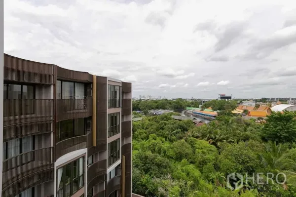 Condominium for sale in Watthana, Bangkok - Modern low‑rise condo facade with curved balconies overlooking lush greenery and skyline in Watthana, Bangkok.