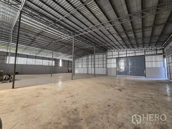 Warehouse for rent in Sai Noi, Nonthaburi - Spacious warehouse interior with high steel truss roof, ventilated louver panels, and polished concrete floor.