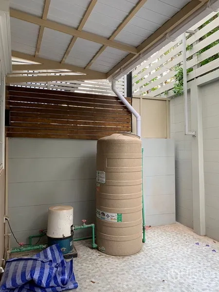 Townhouse for rent in Bang Na, Bangkok - Rear utility area with water tank, pump and tiled floor under a roof