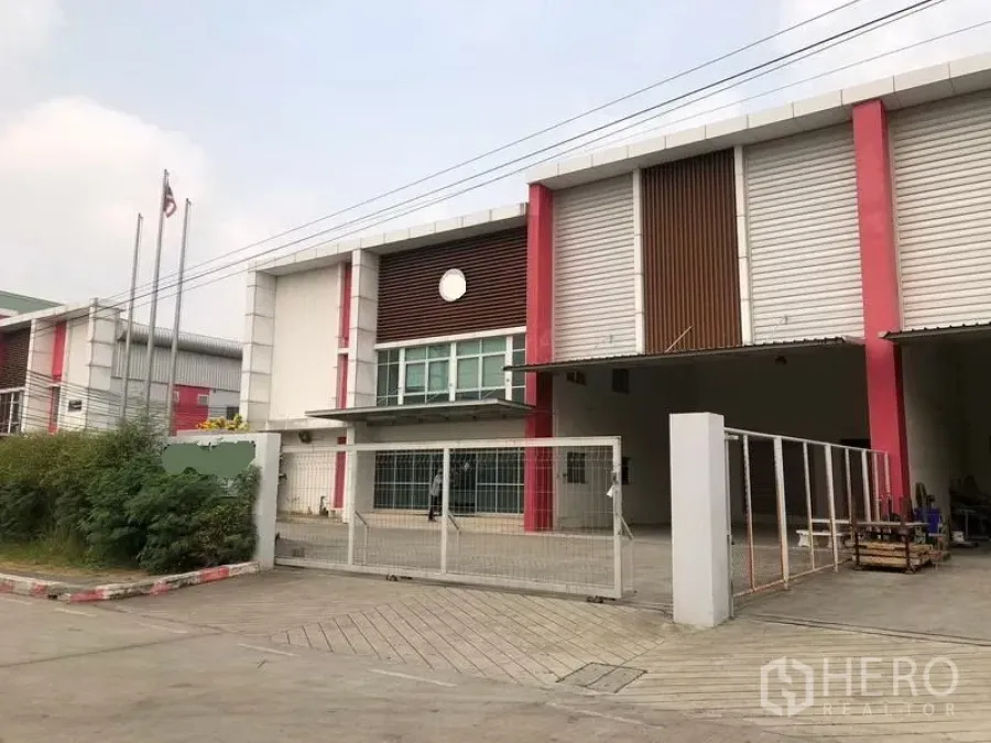 Factory for rent in Bang Sao Thong, Samut Prakan - Modern factory exterior with gated entrance, glass-front office and covered loading bay.