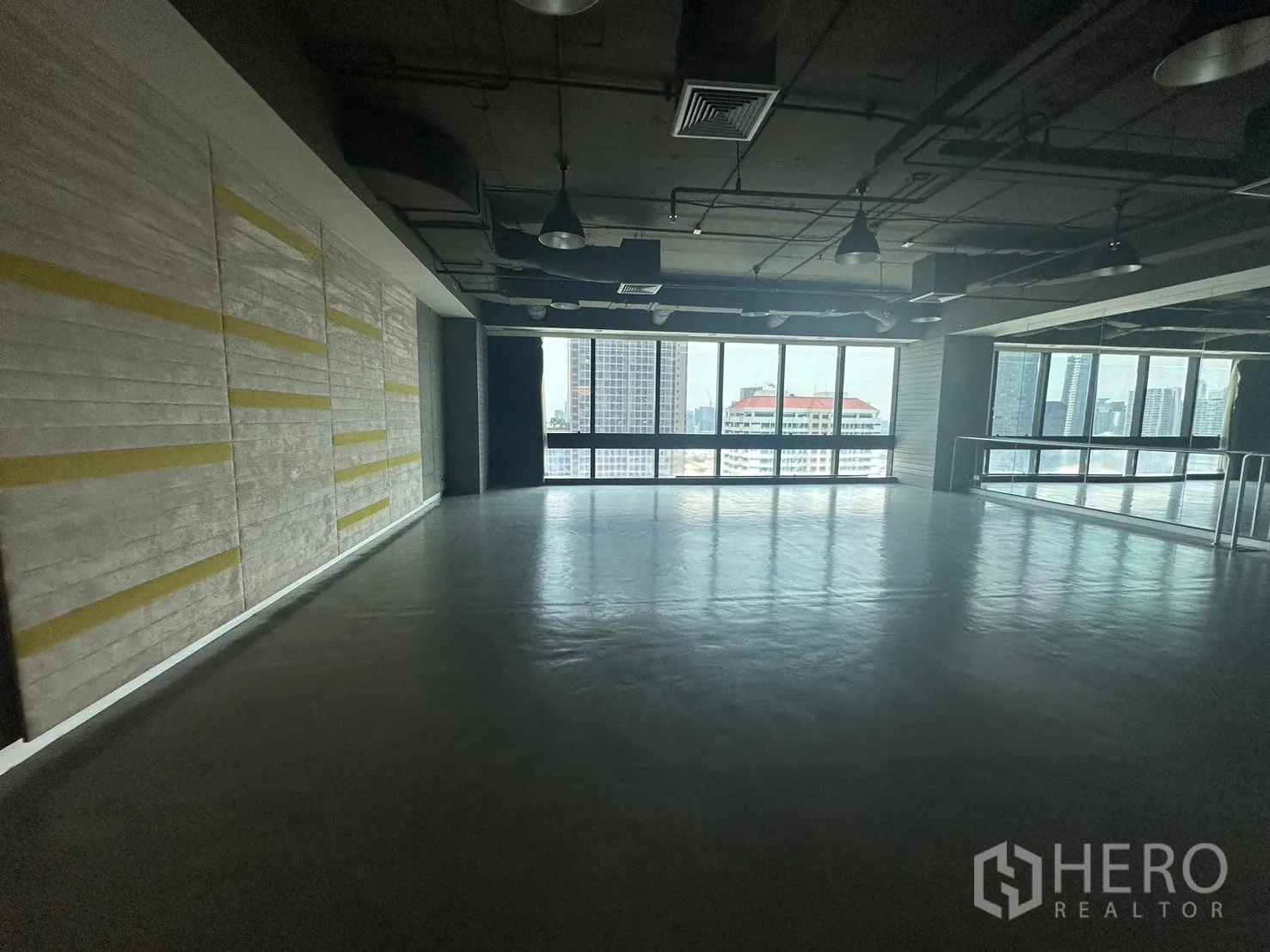 Office Space for rent in Khlong Toei, Bangkok - Large studio-style room with industrial ceiling, mirror wall and city-facing windows.